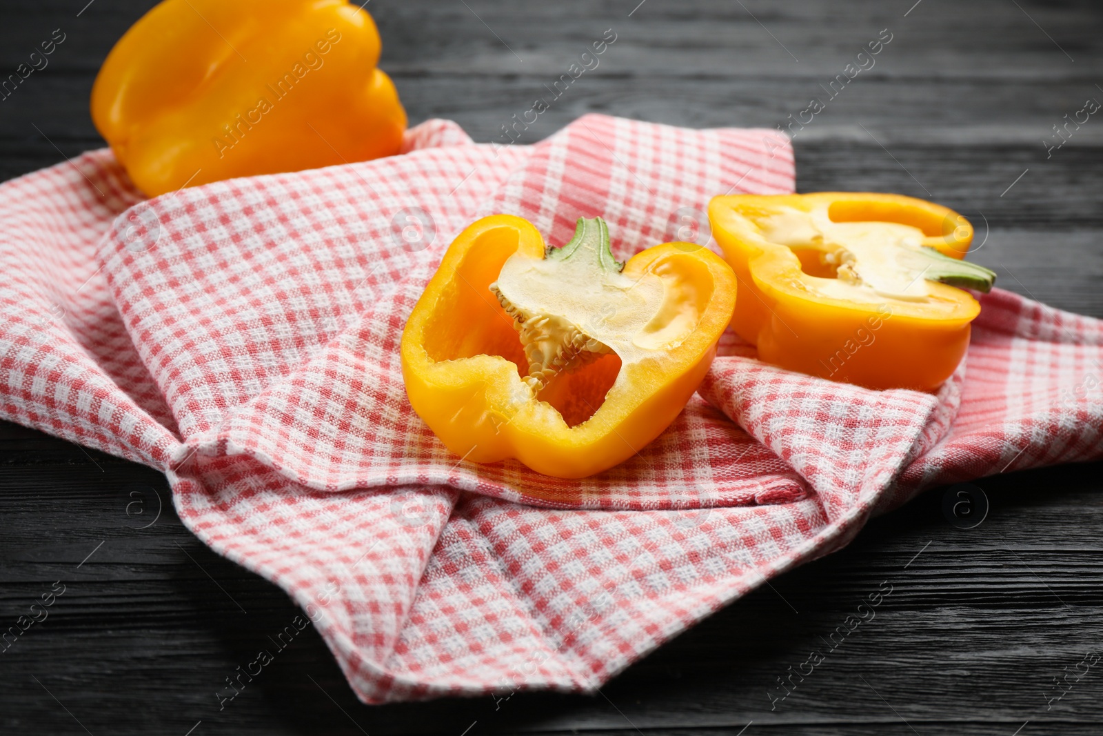 Photo of Kitchen towel and bell peppers on black wooden table