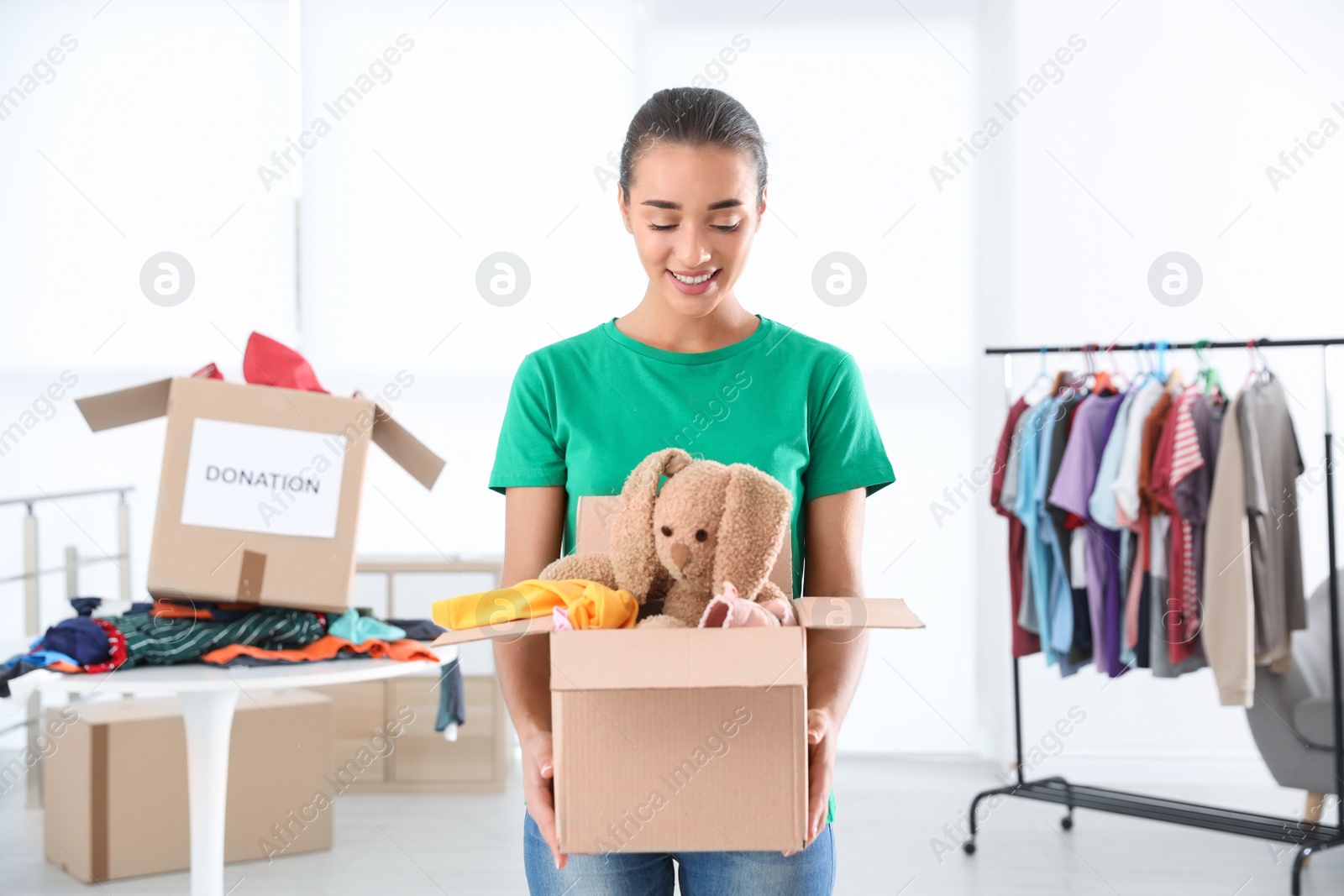 Photo of Young woman holding box with donations indoors
