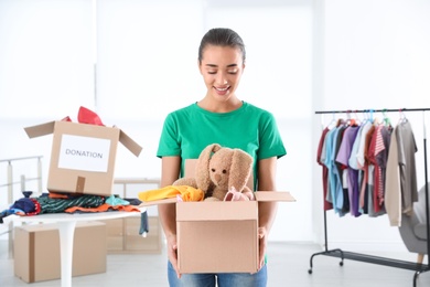 Young woman holding box with donations indoors