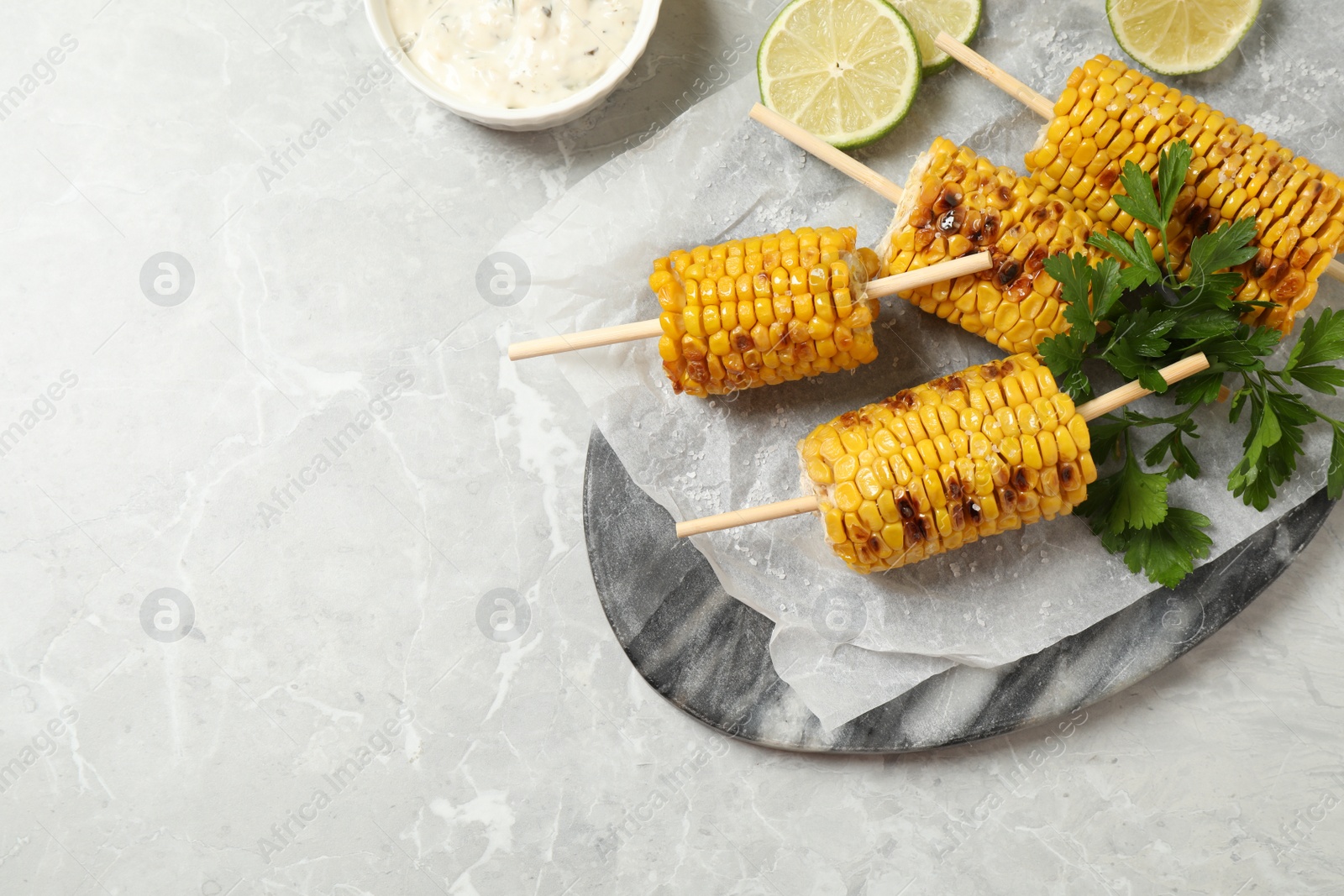 Photo of Tasty grilled corn on light grey table, flat lay. Space for text