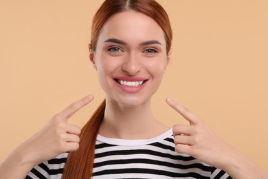 Photo of Beautiful woman showing her clean teeth and smiling on beige background