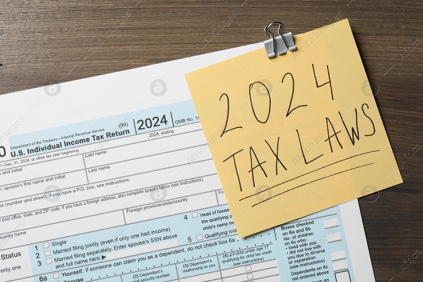 Photo of 2024 tax laws. Form and paper note on wooden table, top view