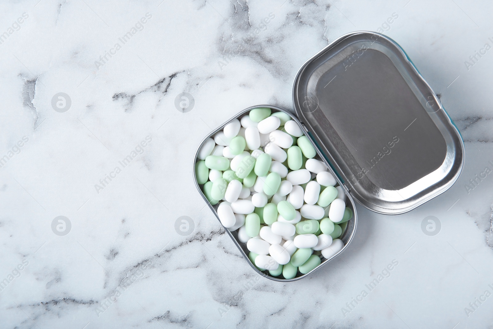 Photo of Open box with tasty mint candies on marble background, top view