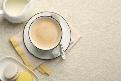 Photo of Tasty cappuccino in cup, milk and macarons on light textured table, flat lay. Space for text