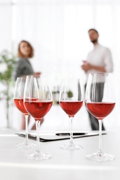 Glasses with delicious wine and blurred people on background