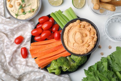 Photo of Plate with delicious hummus and fresh vegetables on white table, flat lay