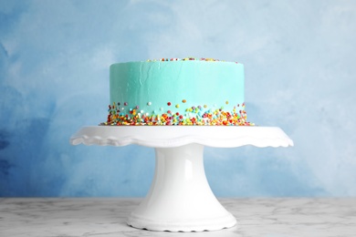 Photo of Fresh delicious birthday cake on stand against color background