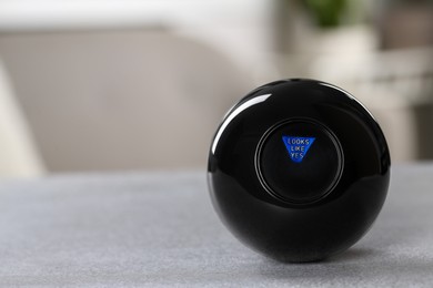 Photo of Magic eight ball with prediction Looks Like Yes on light gray table, closeup. Space for text