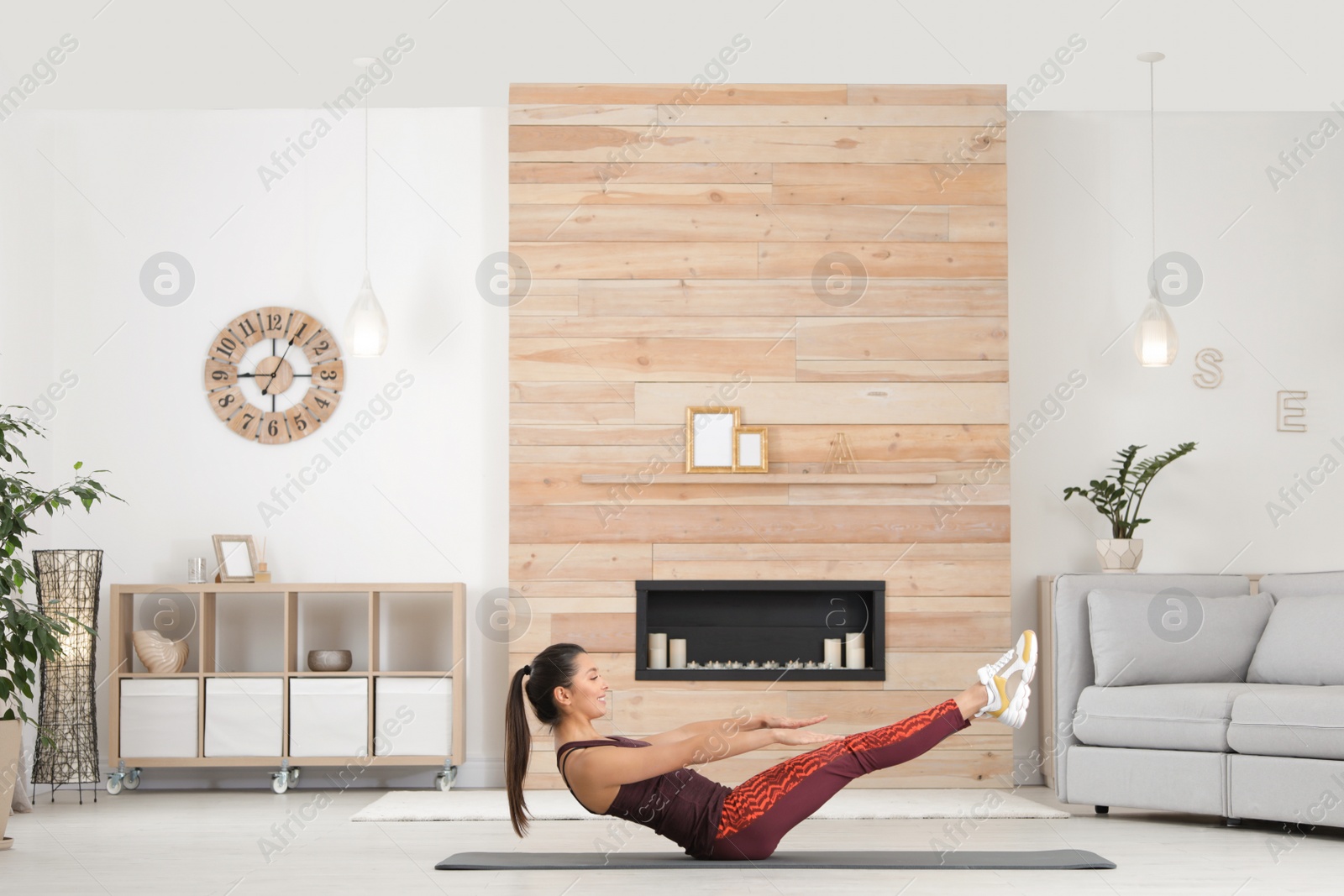 Photo of Young woman in fitness clothes doing exercise at home