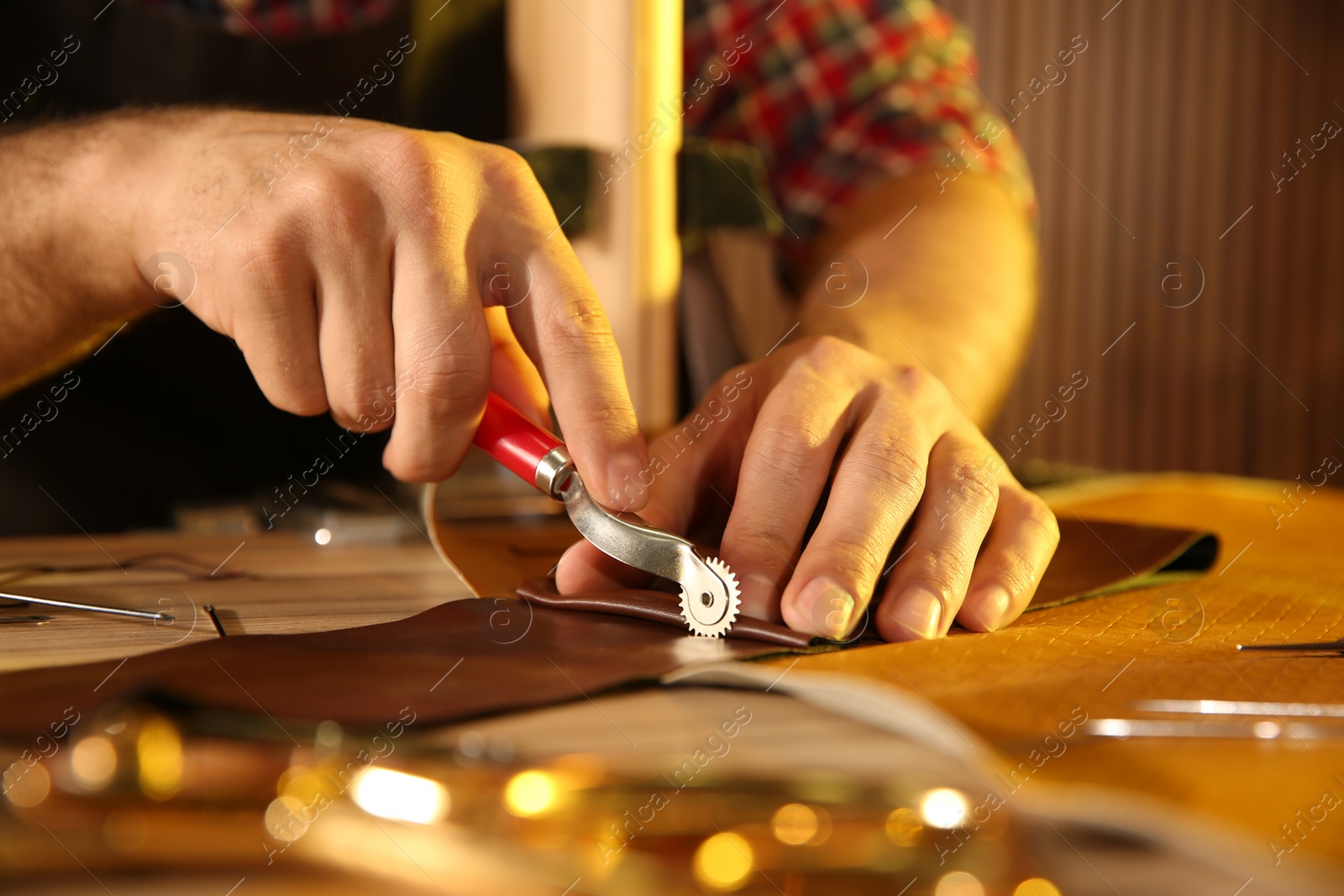 Photo of Man marking leather with roller in workshop, closeup