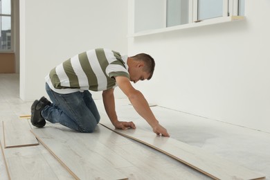 Photo of Professional worker installing new laminate flooring indoors