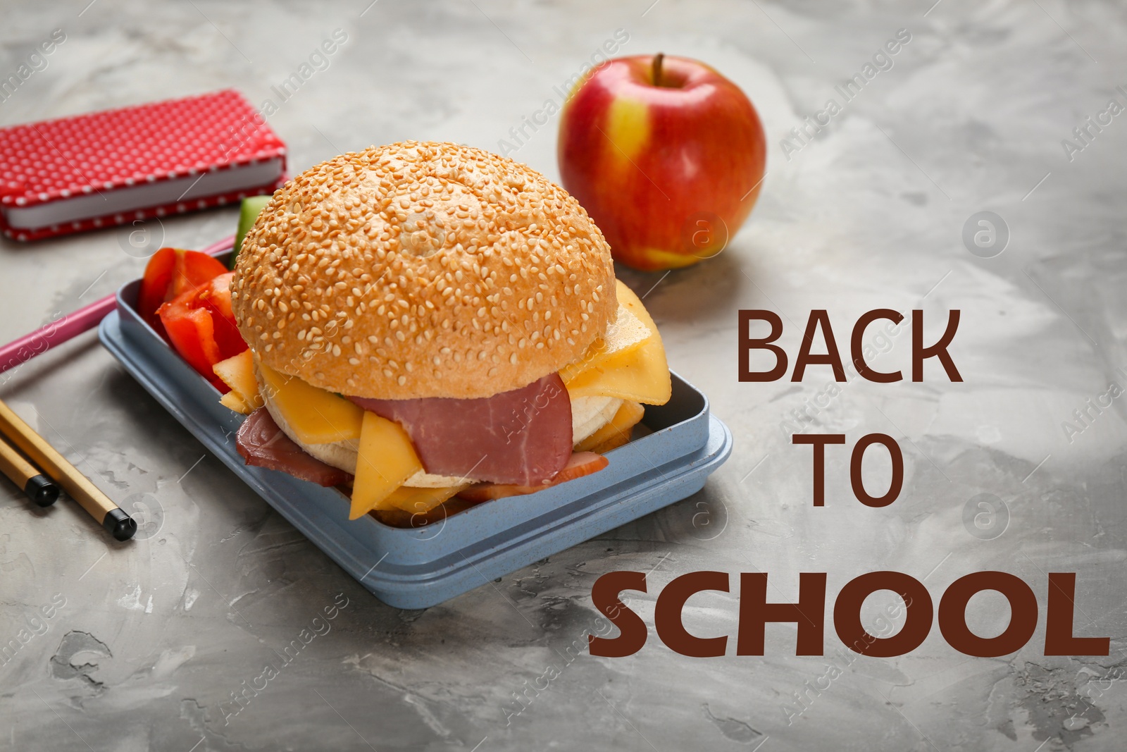 Image of Lunch box with tasty sandwich and stationery on grey table