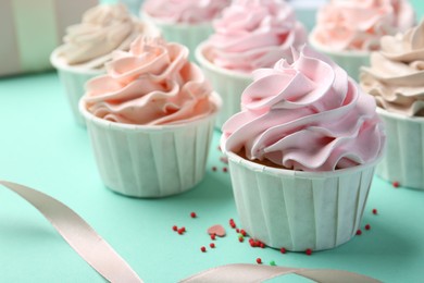 Delicious birthday cupcakes, ribbon and sprinkles on turquoise background, closeup