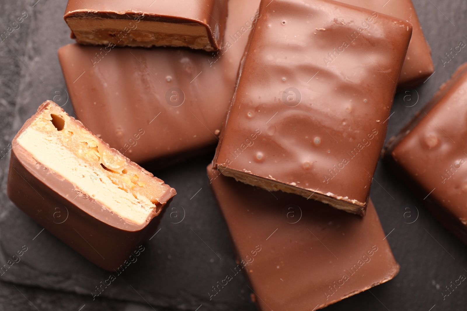 Photo of Tasty chocolate bars with nougat on gray table, top view