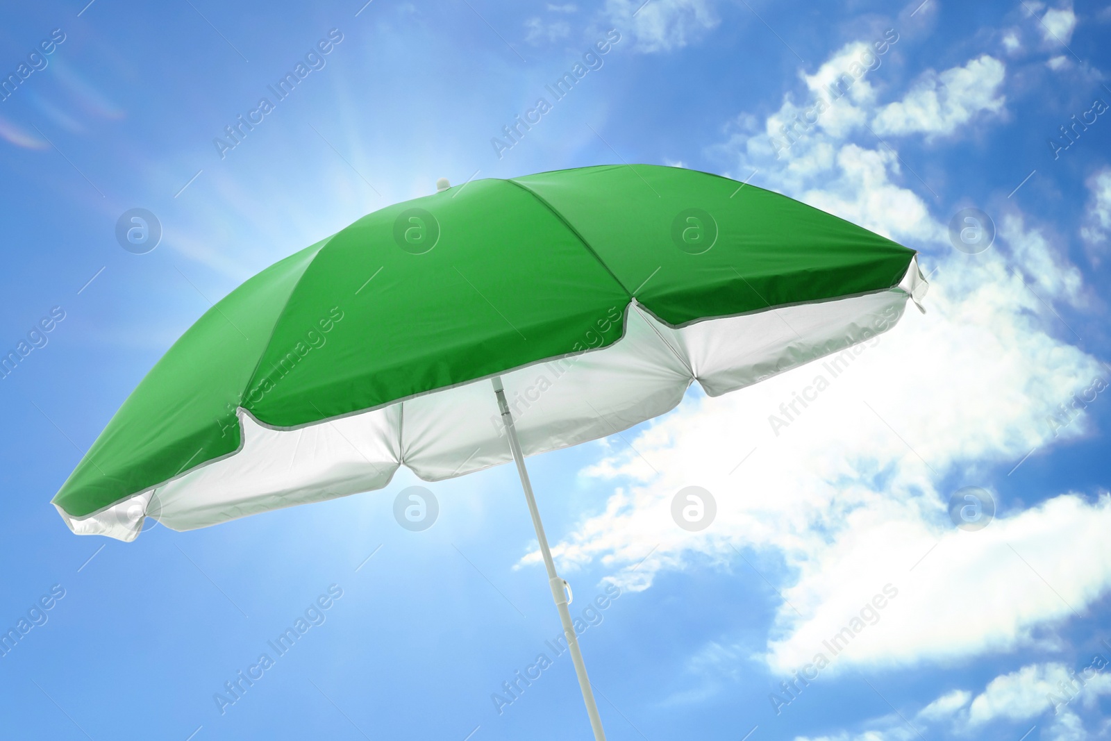 Image of Open big green beach umbrella and beautiful blue sky with white clouds on background