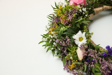 Photo of Wreath made of beautiful flowers on white background, closeup. Space for text