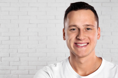 Handsome young man near white brick wall. Space for text