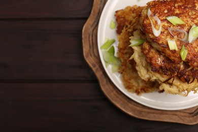 Tasty parsnip cutlets with green onion on wooden table, top view. Space for text