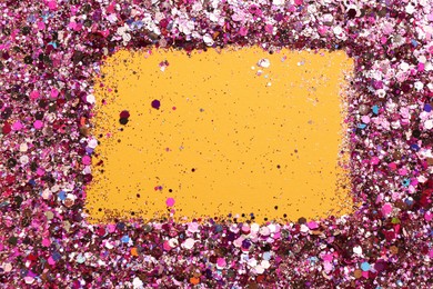 Photo of Frame of shiny bright pink glitter on yellow background, flat lay. Space for text