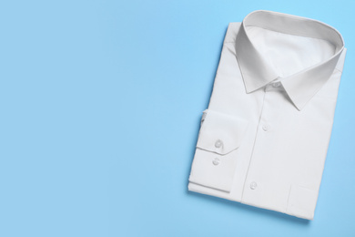 Photo of Stylish white shirt on light blue background, top view with space for text. Dry-cleaning service