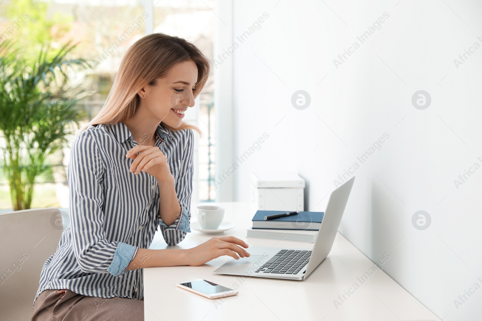 Photo of Young businesswoman using laptop at table in office