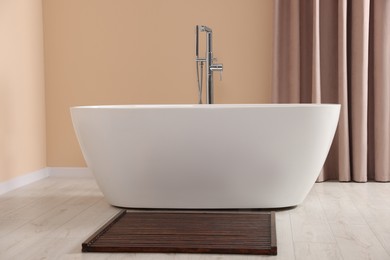 Photo of Stylish bathroom interior with ceramic tub near beige curtains