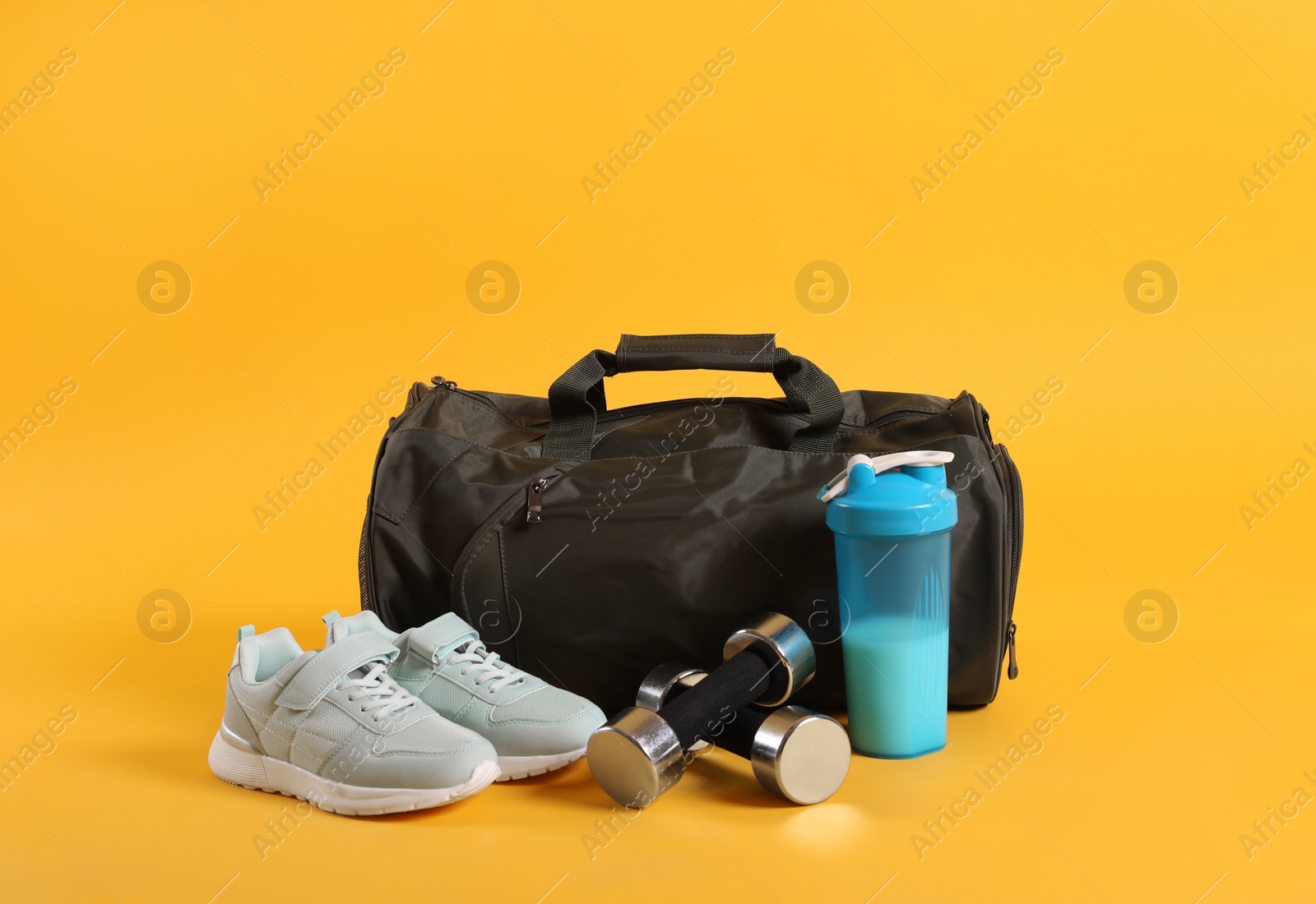 Photo of Sports bag and gym equipment on yellow background