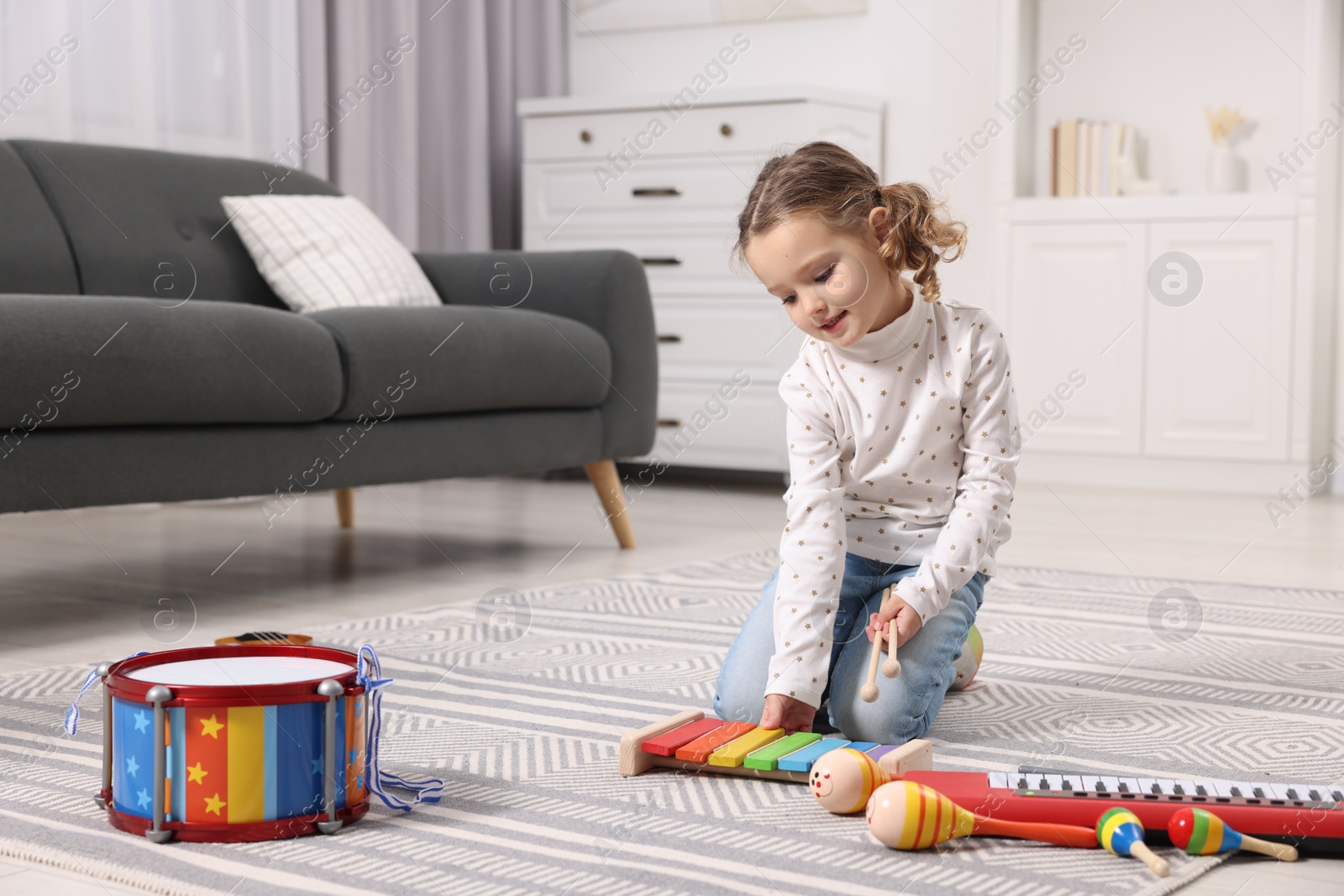 Photo of Little girl playing toy xylophone at home