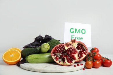 Photo of Tasty fresh GMO free products and paper card on white table