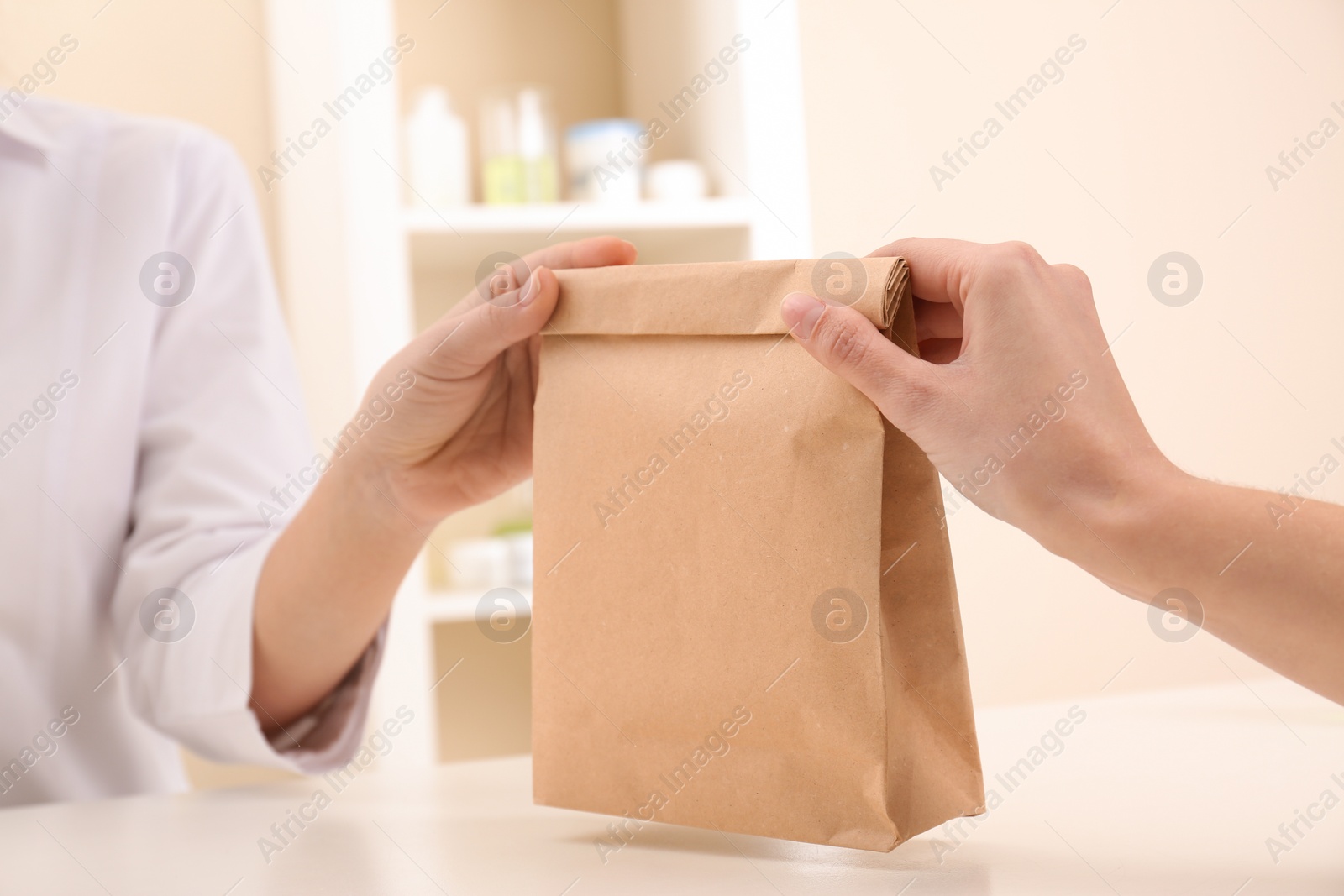 Photo of Woman giving paper bag with order to customer in shop, closeup. Mock up for design