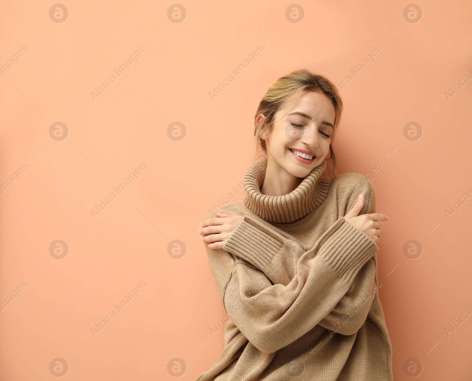 Photo of Beautiful young woman wearing knitted sweater on light brown background. Space for text