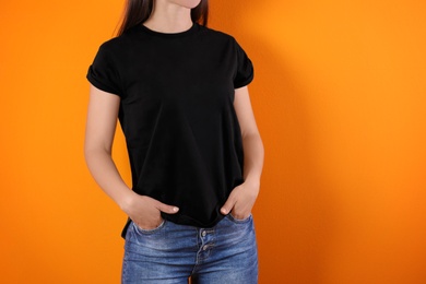 Young woman in black t-shirt on color background. Mockup for design