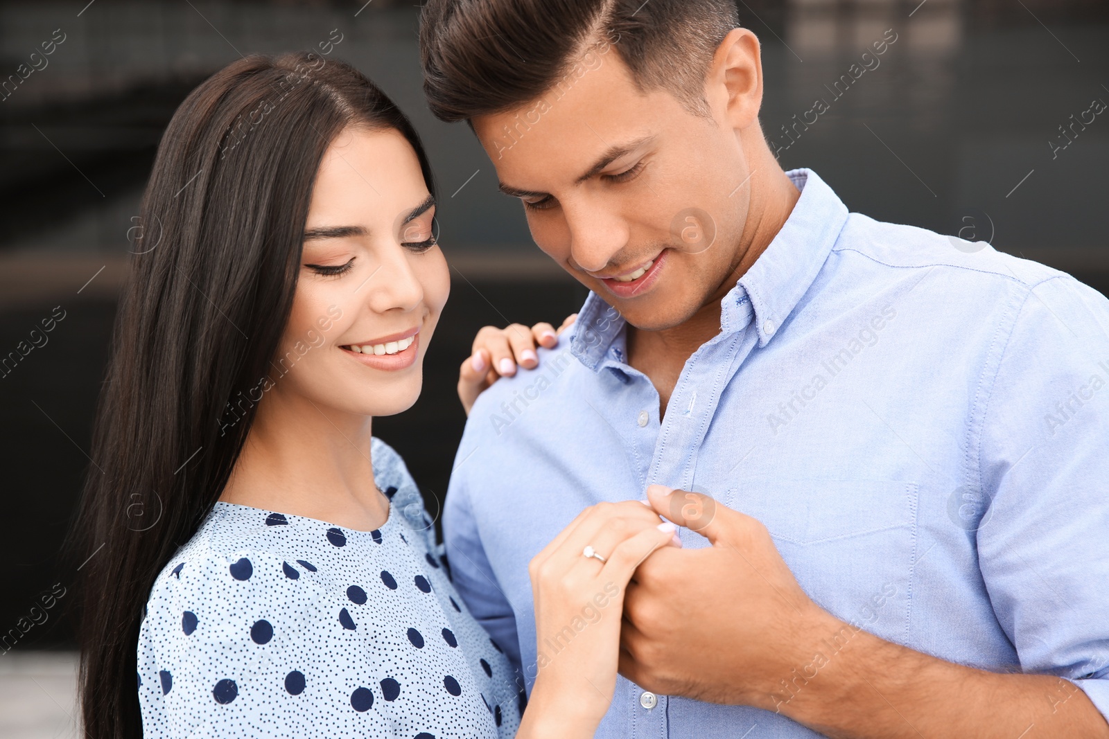 Photo of Lovely couple looking at beautiful engagement ring outdoors