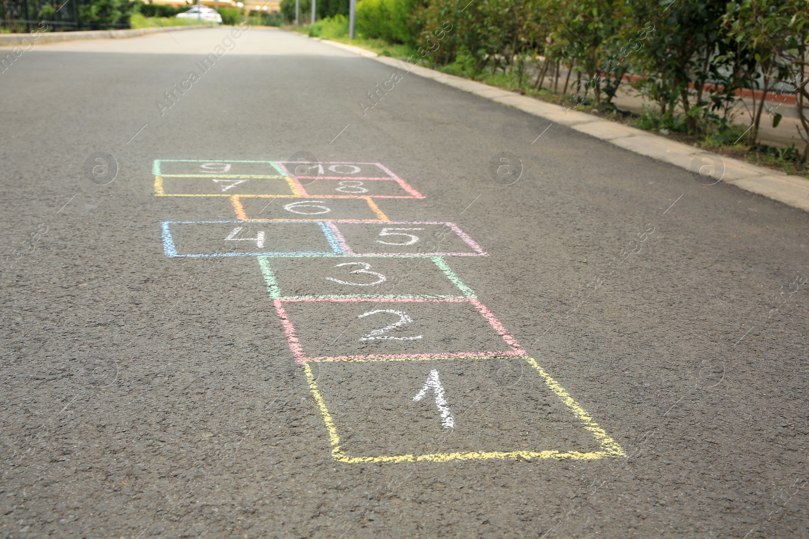 Photo of Hopscotch drawn with colorful chalk on asphalt outdoors