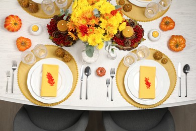 Photo of Autumn table setting with floral decor and pumpkins indoors, top view