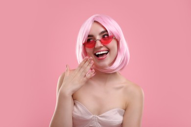 Photo of Pink look. Beautiful girl in wig and bright sunglasses on color background