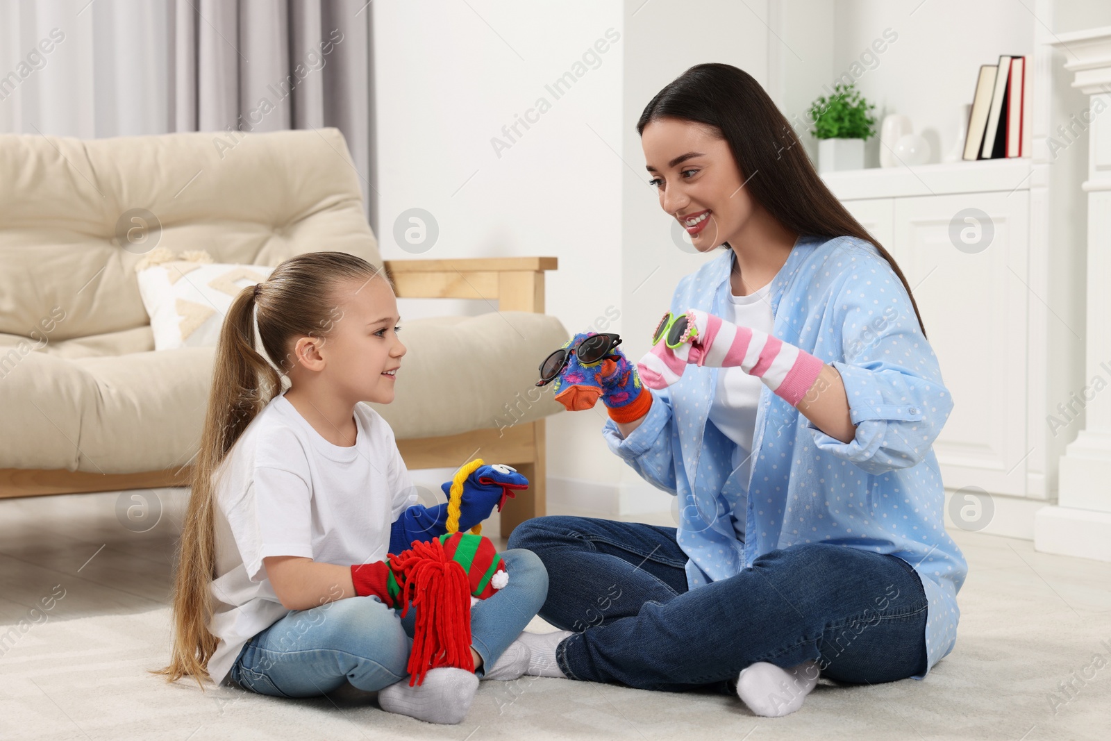 Photo of Happy mother and daughter playing with funny sock puppets together at home