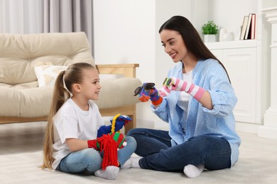 Happy mother and daughter playing with funny sock puppets together at home