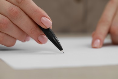 Woman writing on sheet of paper at light table, closeup