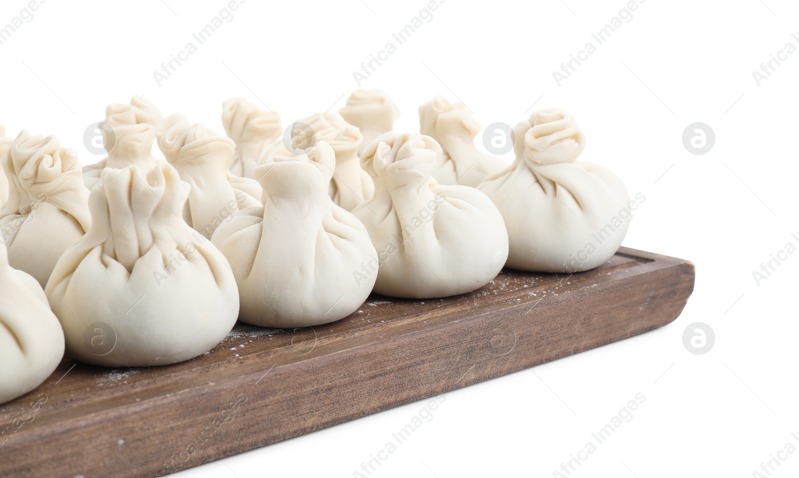 Photo of Wooden board with uncooked khinkali (dumplings) isolated on white. Georgian cuisine
