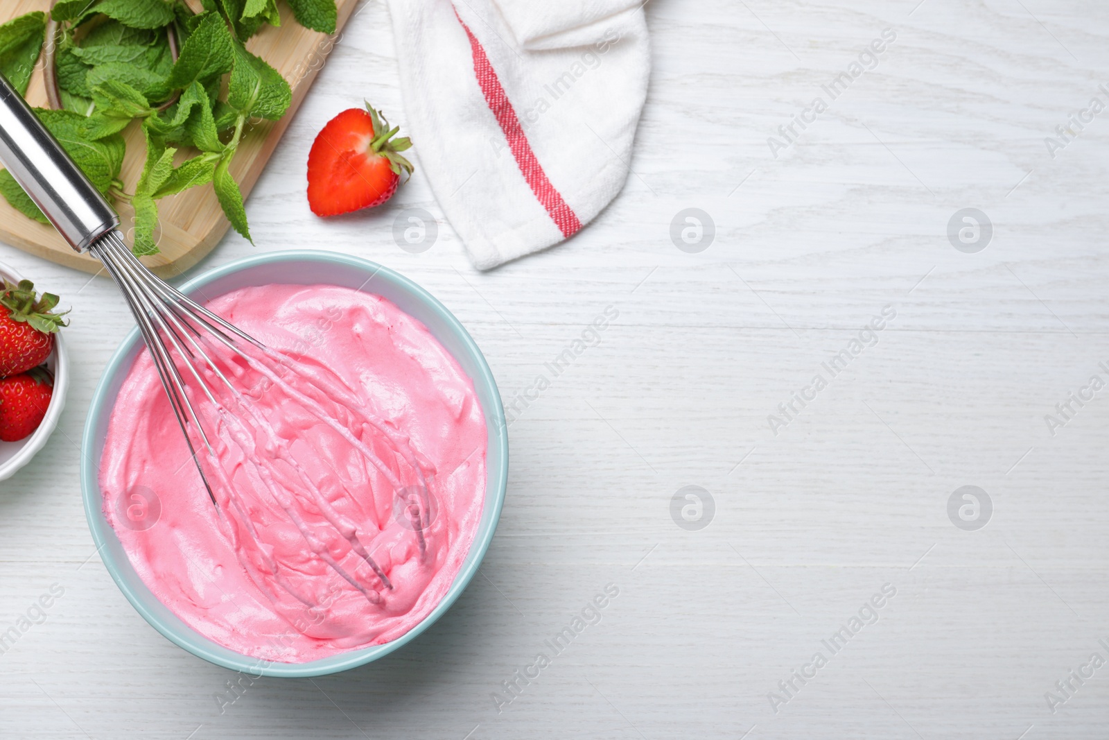 Photo of Strawberry cream with balloon whisk on white wooden table, flat lay. Space for text