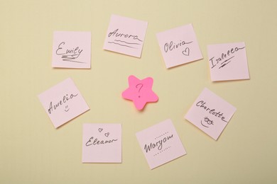 Photo of Choosing baby name. Paper stickers with different names and question mark on beige background, flat lay