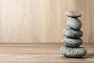 Stack of spa stones on wooden table, space for text