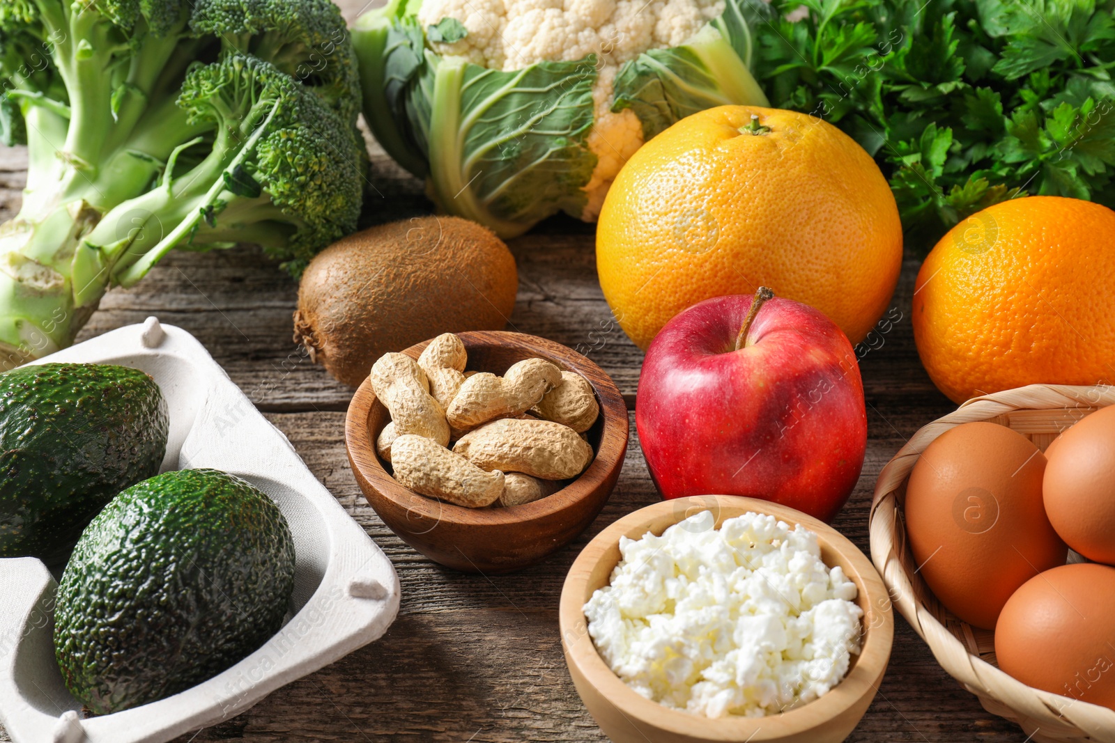 Photo of Healthy meal. Different vegetables and raw eggs on wooden table