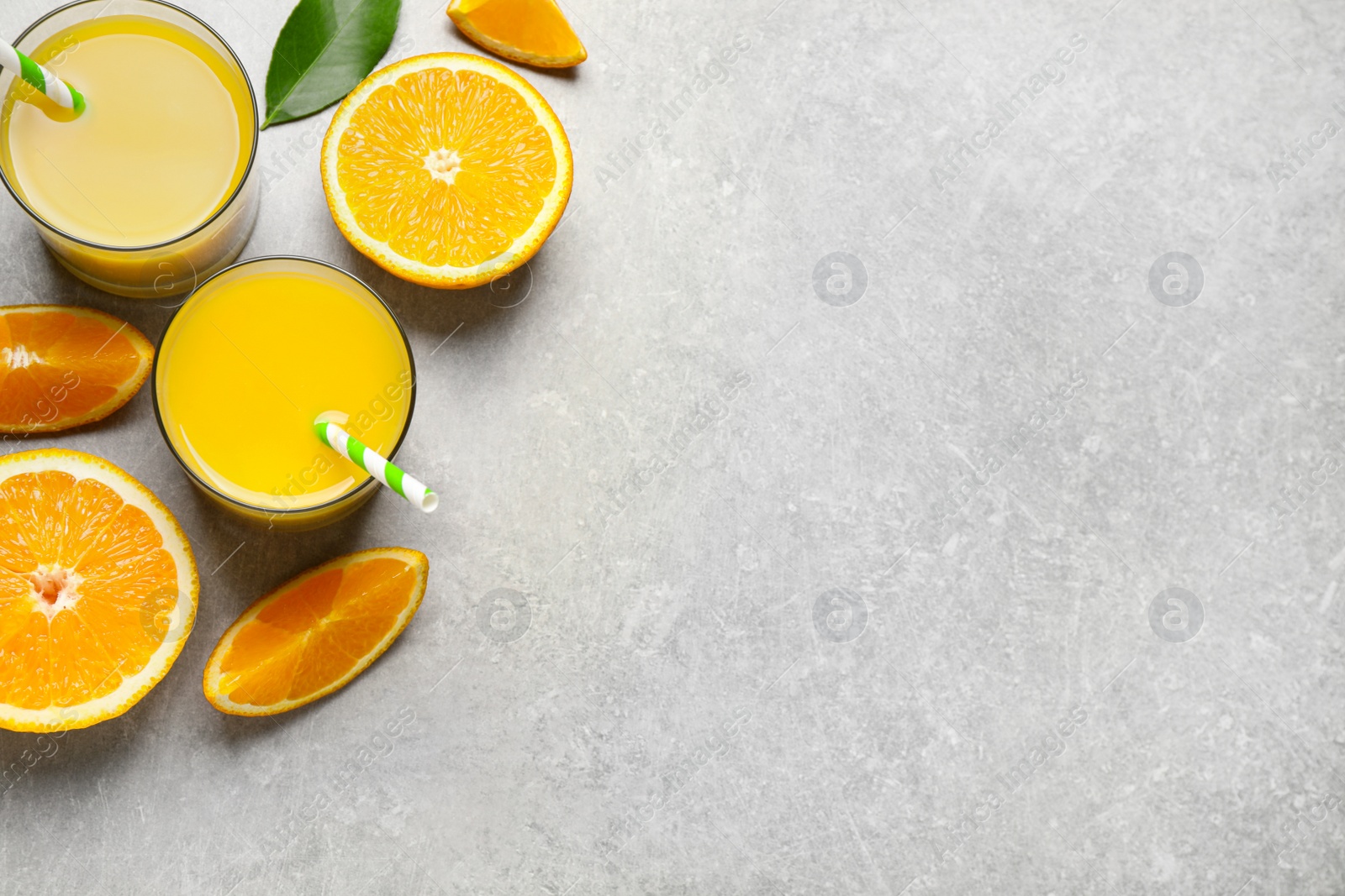 Photo of Glasses of orange juice and fresh fruits on light grey table, flat lay. Space for text