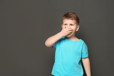 Cute boy suffering from cough on dark background. Space for text