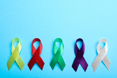 Colorful ribbons on light blue background, flat lay with space for text. World Cancer Day