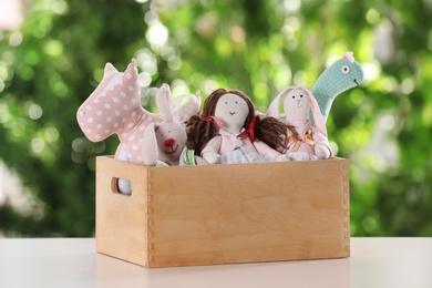 Photo of Box with stuffed toys on table against blurred background