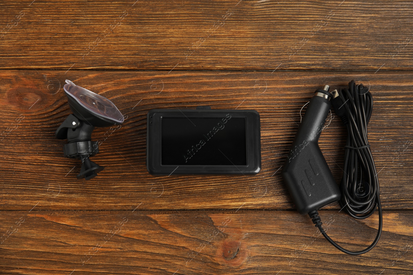 Photo of Modern car dashboard camera, suction mount and charger on wooden background, flat lay