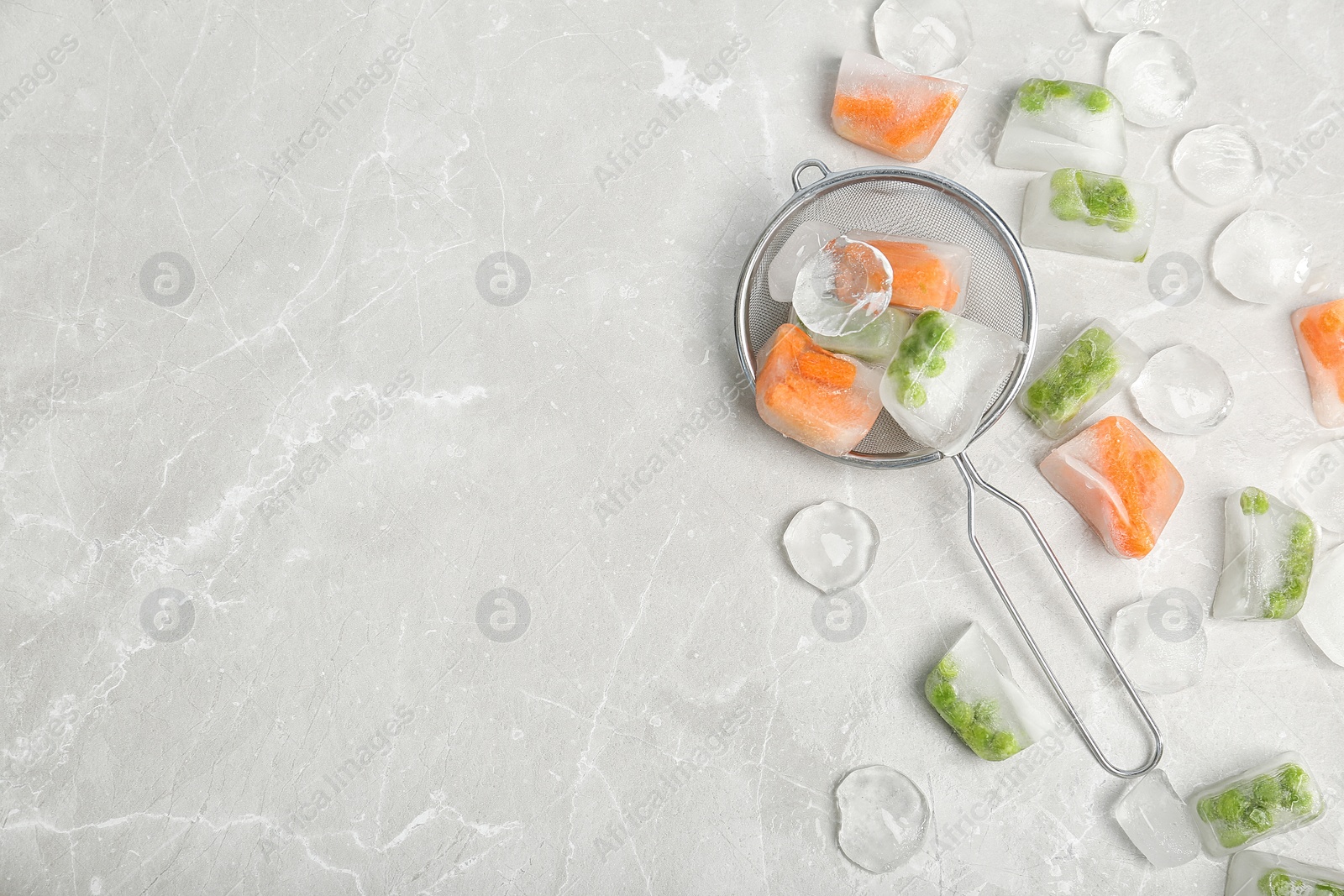 Photo of Frozen vegetables and ice cubes on gray table, flat lay composition with space for text